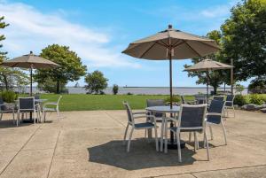 a patio with tables and chairs and an umbrella at The Inn on Maritime Bay, Ascend Hotel Collection in Manitowoc