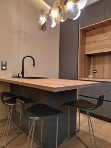 a kitchen with a counter with two stools and a sink at Villagio inn Suite & Spa in Soúlion