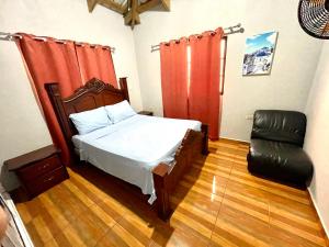 um quarto com uma cama e uma cadeira em Oasis de paz 2 em Jarabacoa