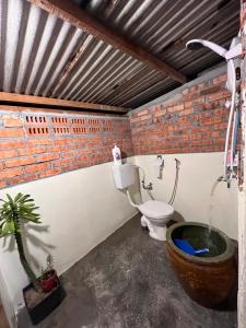 a bathroom with a toilet and a brick wall at 吉胆岛 潮汐民宿 Pulau Ketam Tide Homestay in Bagan Teochew