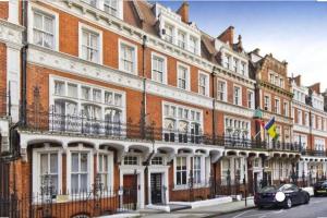 uma fila de edifícios com carros estacionados à frente deles em 2 Bedroom flat in diplomatic enclave in Kensington em Londres