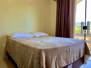 ein Bett in einem Schlafzimmer mit einem großen Fenster in der Unterkunft Refúgio Gramado: Seu Lar Temporário na Cidade dos Sonhos in Gramado