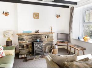 a living room with a stone fireplace and a tv at Middleway Cottage in Saint Blazey