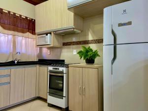 eine Küche mit weißem Kühlschrank und Holzschränken in der Unterkunft Refúgio Gramado: Seu Lar Temporário na Cidade dos Sonhos in Gramado