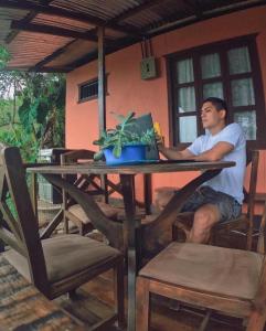 a man sitting at a table with a laptop at Cabañas Colibrí Tayutic in Turrialba