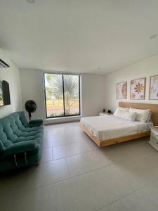 a bedroom with a bed and a couch and a window at Hermosa casa de campo con piscina Girardot flandes in Girardot