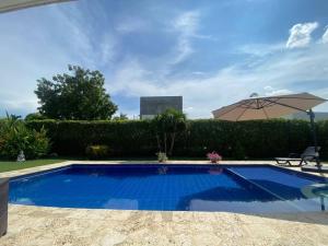 a blue swimming pool with an umbrella and a table at Hermosa casa de campo con piscina Girardot flandes in Girardot