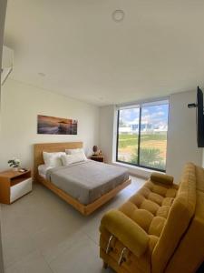 a bedroom with a bed and a couch and a window at Hermosa casa de campo con piscina Girardot flandes in Girardot