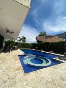 uma piscina com um guarda-sol ao lado de um pátio em Hermosa casa de campo con piscina Girardot flandes em Girardot