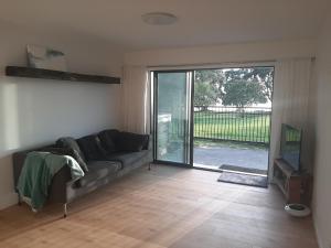 a living room with a couch and a sliding glass door at Ariki beachfront apartment in Snells Beach