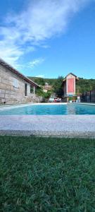 a large swimming pool with grass in front of a building at Casa do Loureiro in Paradela +20 photos
