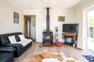 een woonkamer met een bank en een houtkachel bij Turangi Home Family Size in Taupo