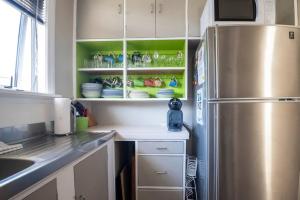 a kitchen with a stainless steel refrigerator and green shelves at Turangi Home Family Size in Taupo