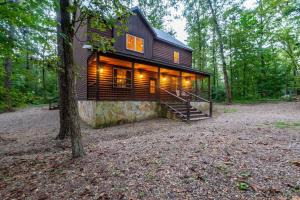 a log cabin in the woods with a tree at Centrally Located Lux Cabin with Hot Tub, Fire Pit, EV Outlet in Broken Bow