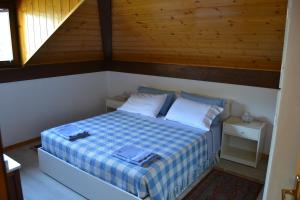a bedroom with a bed with a blue and white checkered blanket at Dimaro Folgarida Appartamento trilocale in villa in Monclassico