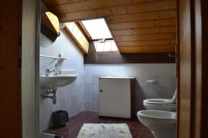 a bathroom with a sink and a toilet and a window at Dimaro Folgarida Appartamento trilocale in villa in Monclassico +5 photos