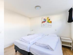 two beds in a room with white walls at Woonark De Woude in Uitgeest