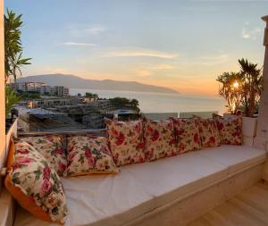 a white couch with pillows on a balcony with the ocean at Sea View Apartment with Veranda Beach Amazing in Vlorë