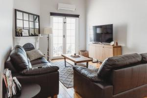 a living room with two leather couches and a television at Hargreaves Cottage - close to CBD in Bendigo