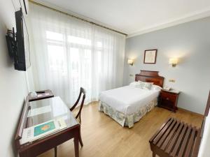 a bedroom with a bed and a table and a window at Rias Bajas in Pontevedra