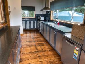 a kitchen with black counters and a wooden floor at Elevated 3BR, ocean views, pool table, Pirates Bay in Eaglehawk Neck