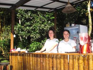Dwie kobiety stoją przy drewnianym blacie. w obiekcie Acqua Jungle Glamping & Room w mieście Abraão