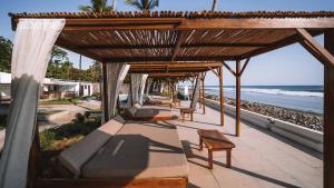 a group of beds on a patio next to the beach at Coco Surf Tropical Village in La Libertad