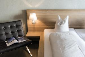 a bedroom with a bed and a chair with a pillow at Hotel des Alpes in Flims