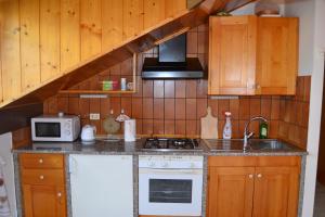 a kitchen with a stove and a sink and a microwave at Dimaro Folgarida Appartamento trilocale in villa in Monclassico