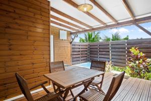 une terrasse en bois avec une table et des chaises en bois dans l'établissement Bel'oasis, au Lamentin