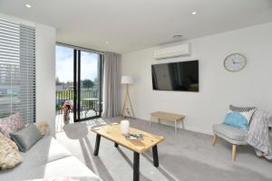 a living room with a tv and a table at Worcester Terrace One - Christchurch Holiday Homes in Christchurch