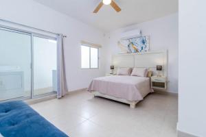 um quarto branco com uma cama e um sofá azul em Tonacalli, departamentos privados con alberca em San Carlos
