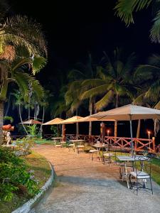 een groep tafels en parasols in een resort bij La Playita Resort in Lalauigan