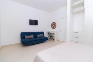 um sofá azul num quarto branco com uma cama em Tonacalli, departamentos privados con alberca em San Carlos
