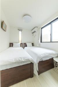 two beds in a bedroom with white walls and a window at SKYTREE HOUSE in Tokyo