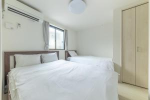 a bedroom with two white beds and a window at SKYTREE HOUSE in Tokyo