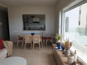a living room with a table and chairs and a kitchen at Vue panoramique Front de merla perle in Casablanca
