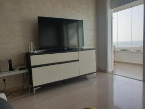 a living room with a television on a white cabinet at Vue panoramique Front de merla perle in Casablanca