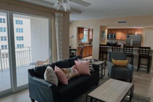 a living room with a black couch and a kitchen at Opus Condominiums in Daytona Beach Shores