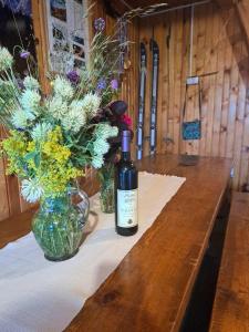 una bottiglia di vino seduta su un tavolo con fiori di Stara kuca u Virku a Žabljak