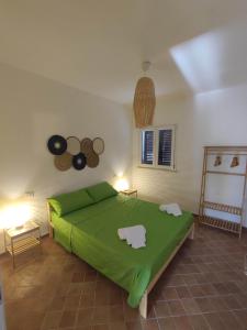 a bedroom with a green bed in a room at Casa Porto Palo in Porto Palo