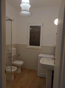 a bathroom with a toilet and a sink and a mirror at Casa Porto Palo in Porto Palo