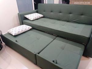 a green couch with two pillows on top of it at Qilala DualView by The Shore in Kota Kinabalu