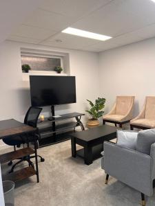 ein Wohnzimmer mit einem TV, einem Sofa und Stühlen in der Unterkunft Well furnished 1 Bedroom Basement Suite in Winnipeg