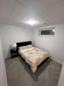 Well furnished 1 Bedroom Basement Suite في وينيبيغ: غرفة نوم بسرير في غرفة بيضاء