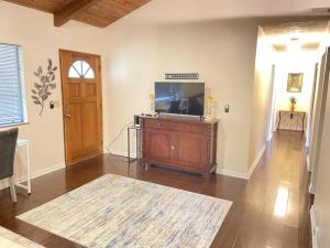 a living room with a flat screen tv on a entertainment center at THE MANONO HOUSE - Peaceful, Private 3Bd 2Bath Home near HILO, with AC! in Keaau
