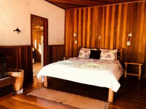 um quarto com uma cama num quarto com paredes de madeira em Pousada chalés Binitz em Visconde de Mauá