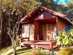 a small wooden cabin with a deck in the woods at Pousada chalés Binitz in Visconde De Maua