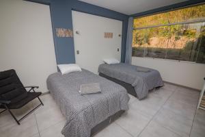 Cette chambre dispose de deux lits, d'une chaise et d'une fenêtre. dans l'établissement HOSTAL MONTALVO VALLE, à Moquegua