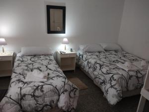 2 camas en una habitación con 2 mesas y un espejo en Departamento Juana-Franch en Salta